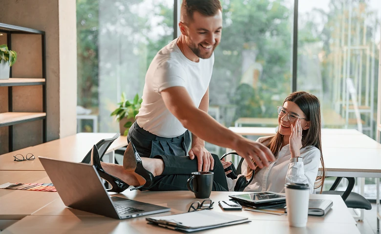 Two people working at a table with laptops