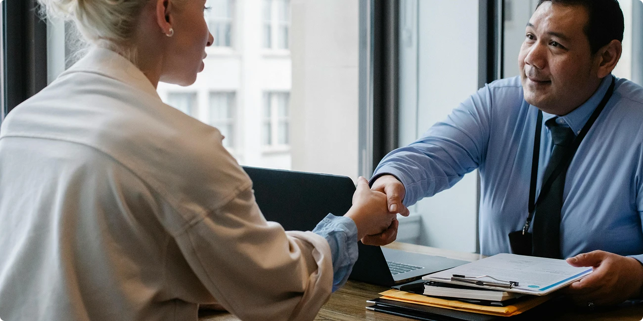 Two people shaking hands across a desk
